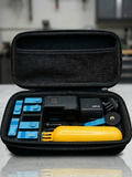 Black carrying case with electronic devices and tools on a reflective surface